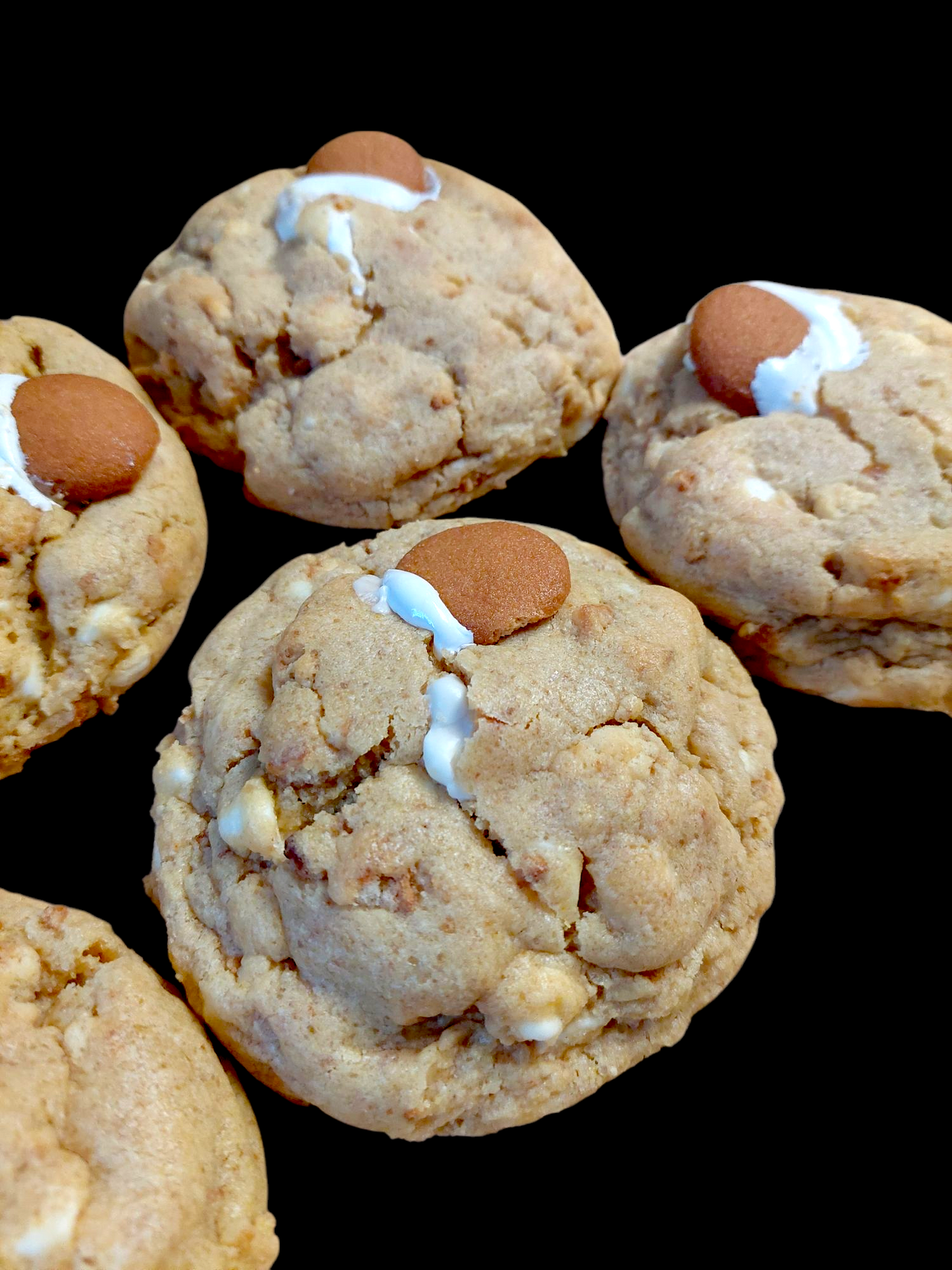 Close-up of Big Ass Banana Pudding cookies with banana pudding dough, Nilla Wafer pieces, gooey marshmallows and marshmallow drizzle on top.